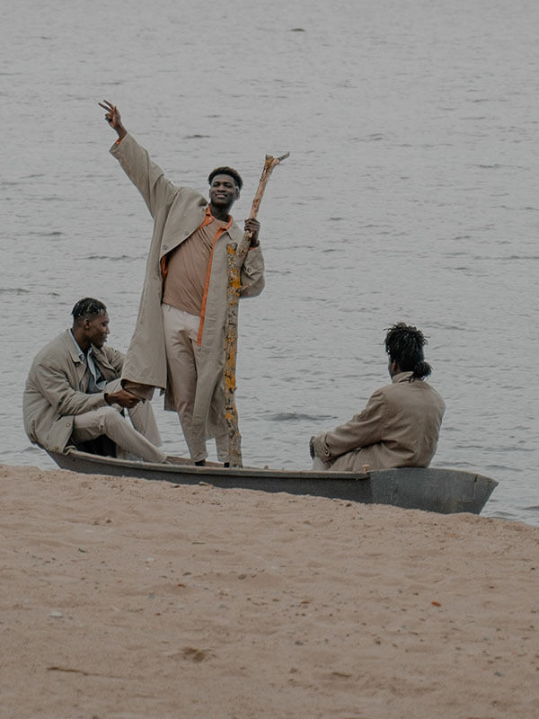 Three men in boat, one standing with arm up.