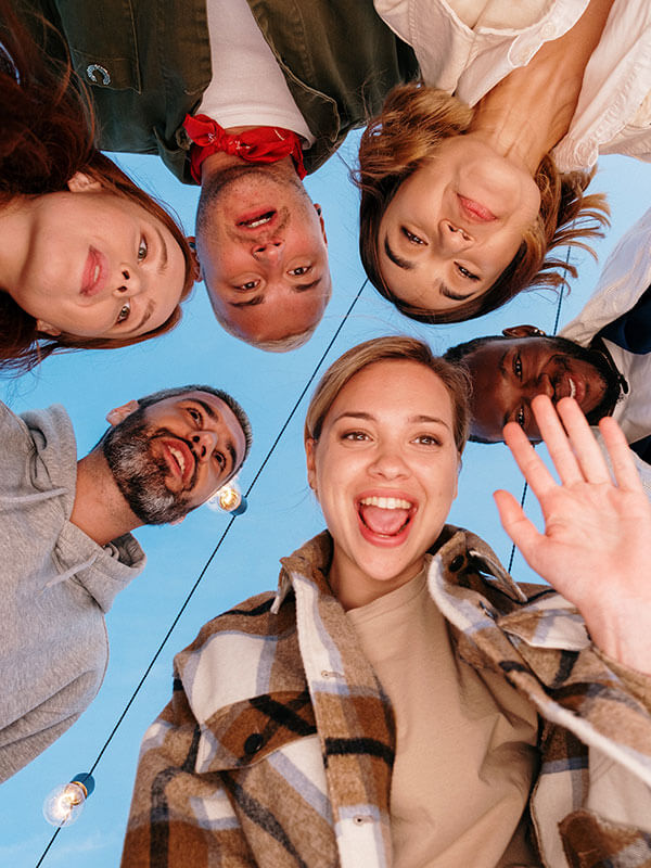 Upward view of group of friends smiling.