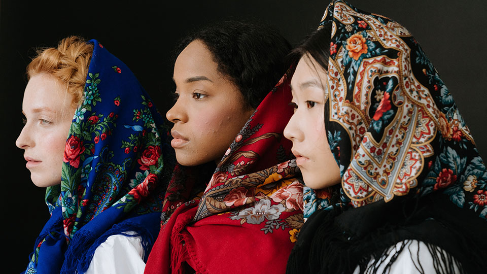 Three women wearing scarves looking to the left.