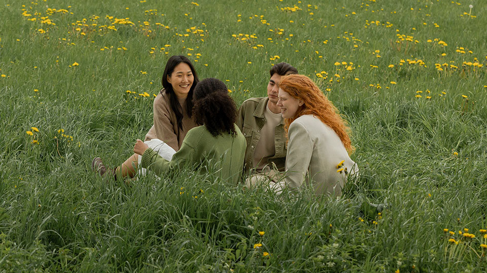 Group of friends sitting in grass smiling.