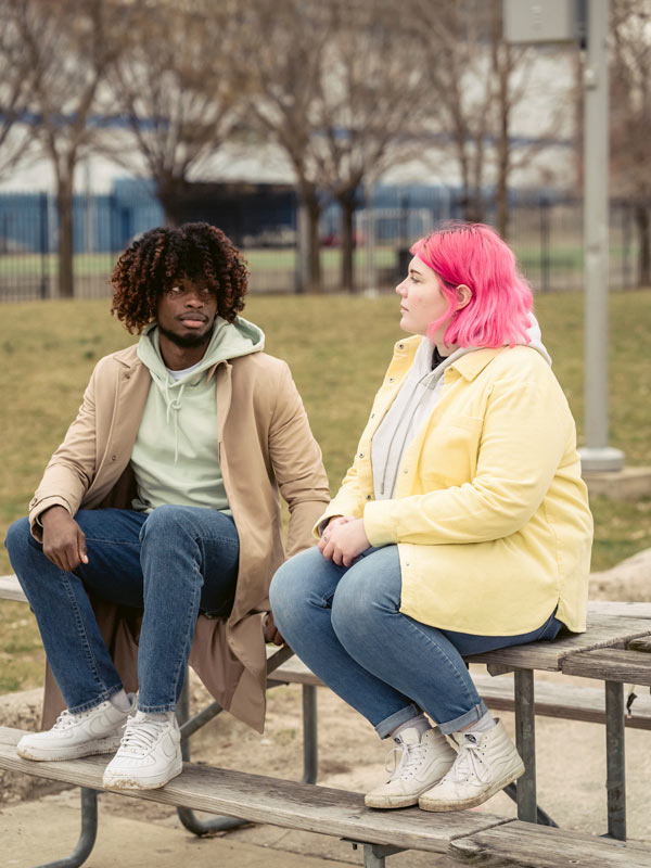 A man and woman sitting on top of a picnic table talking