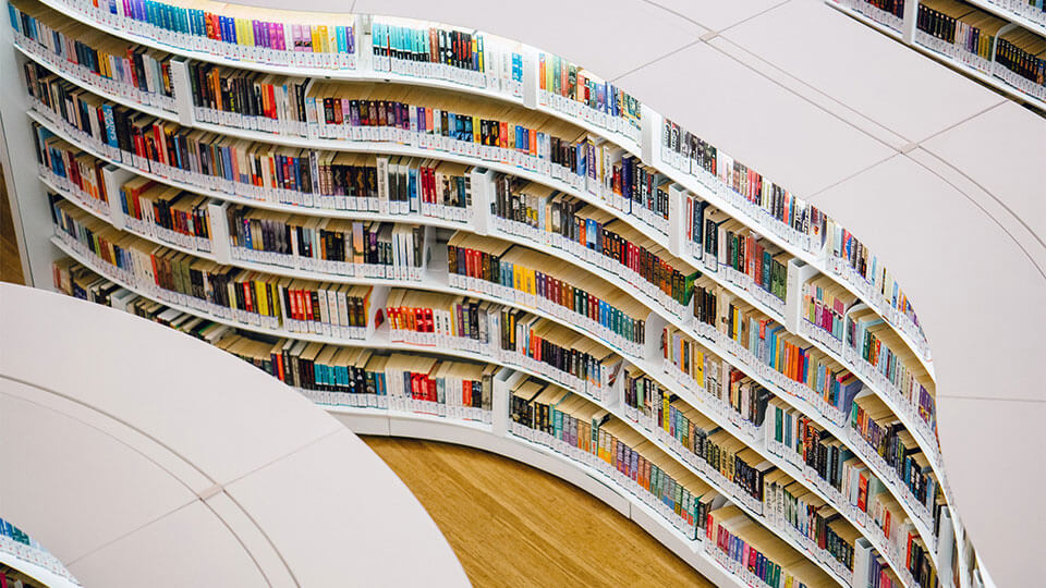 A curved library shelf full of books.