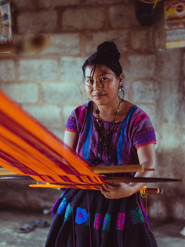 Woman wearing traditional clothes working loom.