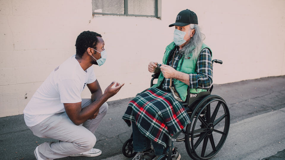 Man speaking to person in wheelchair.