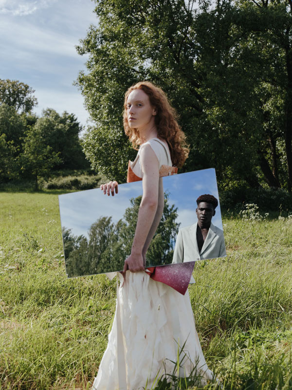 Woman holding mirror in grass field.