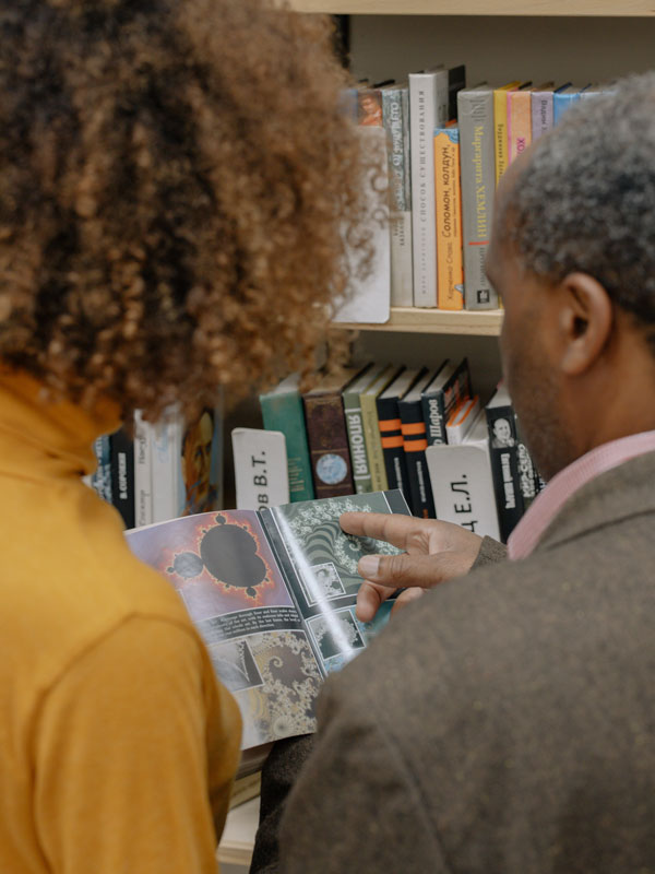 Man and woman looking at pages in book.