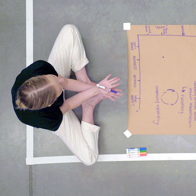 A woman sitting on the floor drawing a chart